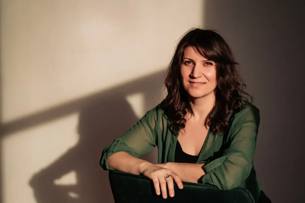 Főoldal 2 Langer Rozi mosolyogva ül, meleg esti fényben, a falon a saját árnyéka